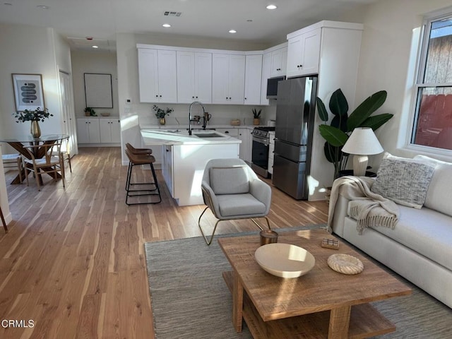 living room with light wood-style flooring, visible vents, and recessed lighting