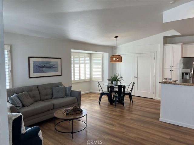 living area featuring dark wood-type flooring, lofted ceiling, and baseboards