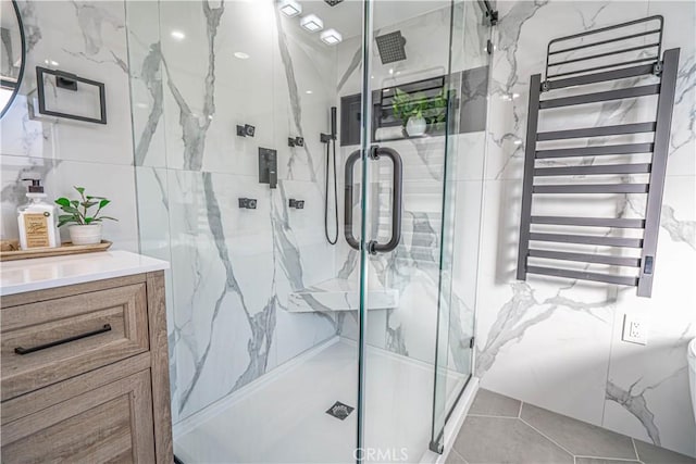 bathroom featuring vanity, tile walls, radiator, and a marble finish shower