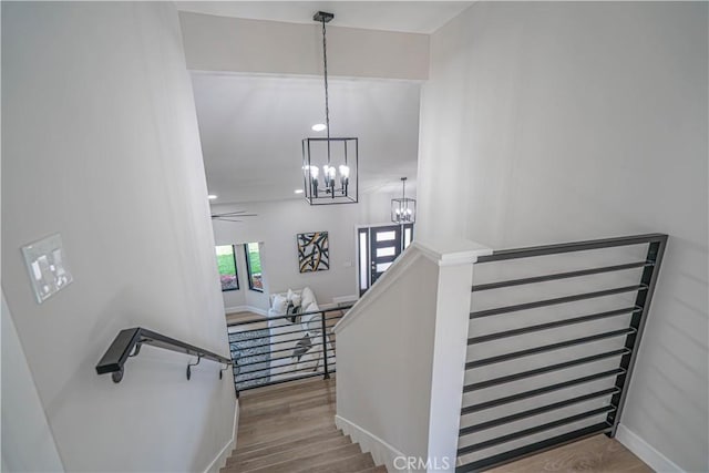 staircase with baseboards, a notable chandelier, and wood finished floors