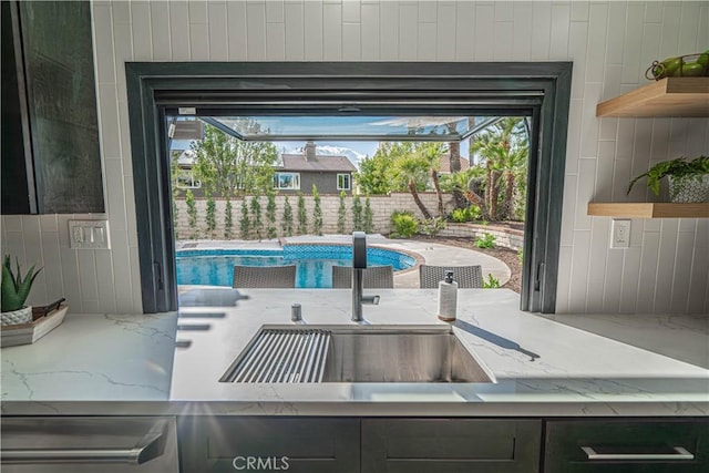 interior space featuring open shelves, light stone countertops, backsplash, and a sink