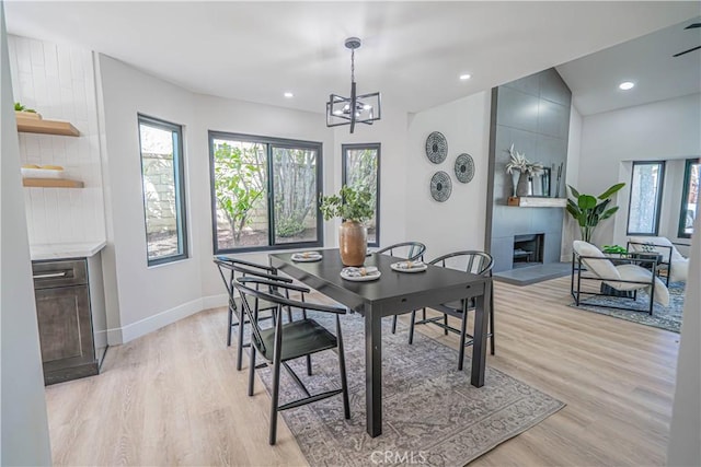 dining space featuring recessed lighting, baseboards, light wood-style flooring, and a tiled fireplace