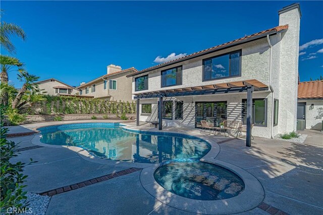 view of swimming pool with a patio area, fence, a pool with connected hot tub, and a pergola