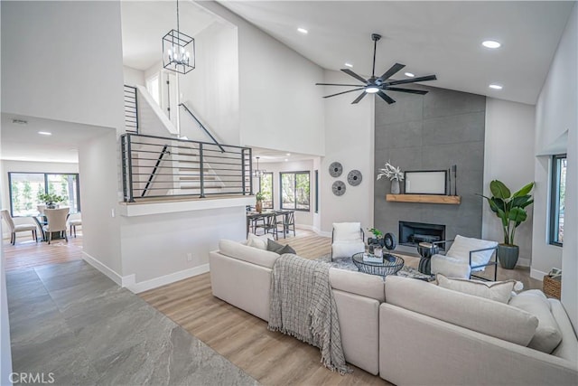 living area with baseboards, high vaulted ceiling, wood finished floors, and a fireplace