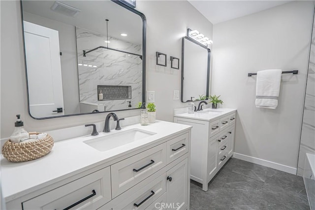 bathroom featuring a marble finish shower, two vanities, baseboards, and a sink