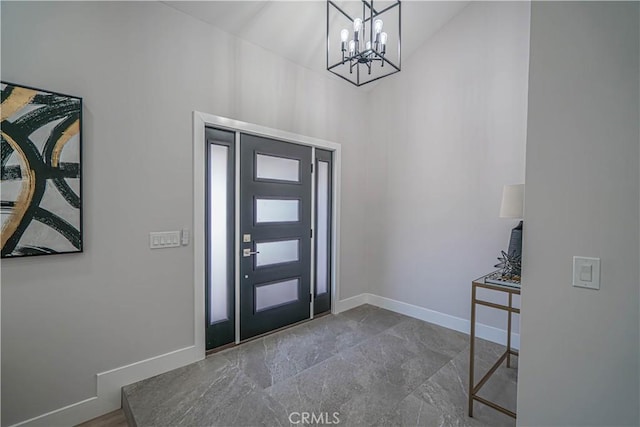 foyer entrance featuring a notable chandelier and baseboards