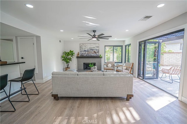 living area with visible vents, baseboards, recessed lighting, a fireplace, and light wood-style floors