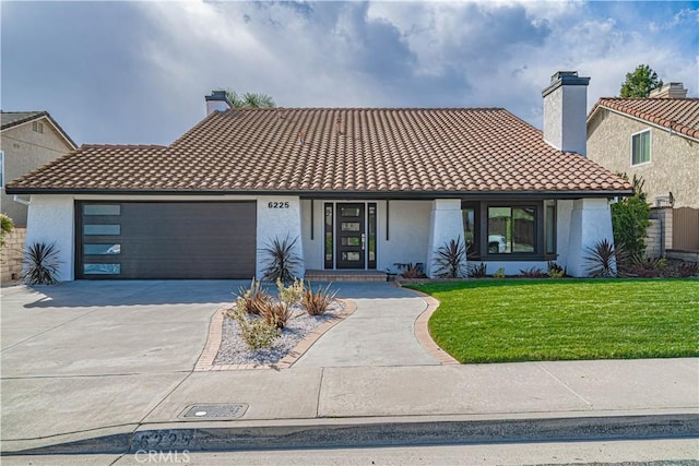 view of front of house featuring driveway, stucco siding, a chimney, a front lawn, and a tile roof