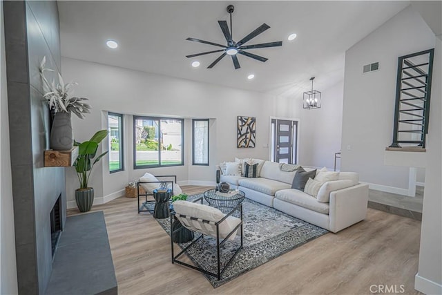 living room featuring recessed lighting, light wood-style floors, visible vents, and high vaulted ceiling