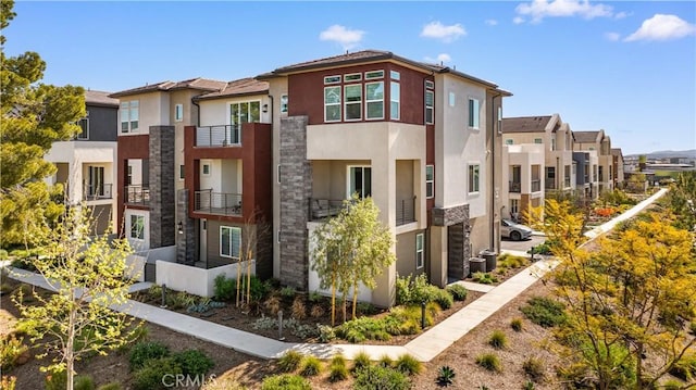 exterior space with stone siding, central AC, a residential view, and stucco siding