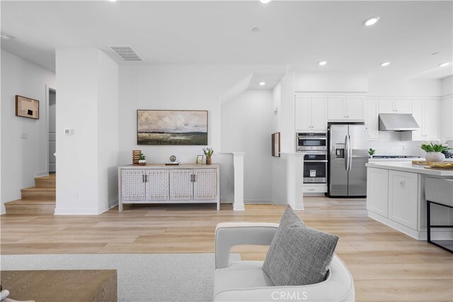 living area featuring recessed lighting, stairway, baseboards, visible vents, and light wood-style floors