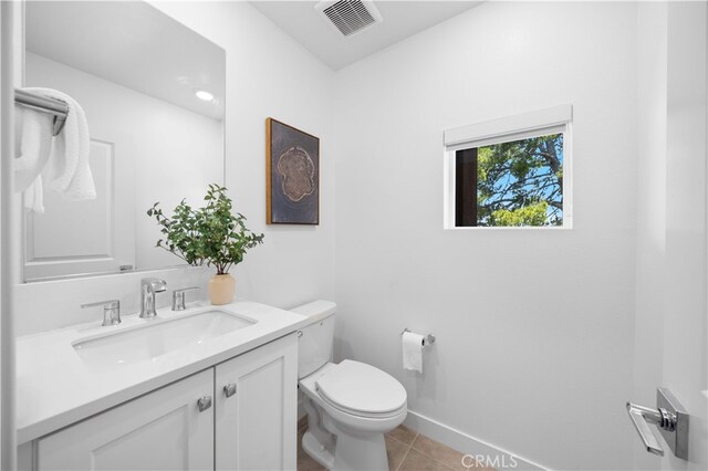 bathroom featuring toilet, vanity, visible vents, tile patterned flooring, and baseboards