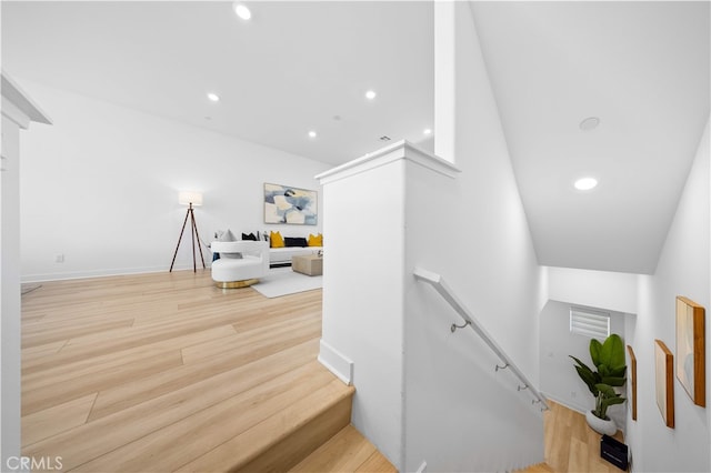 stairs featuring wood finished floors and recessed lighting