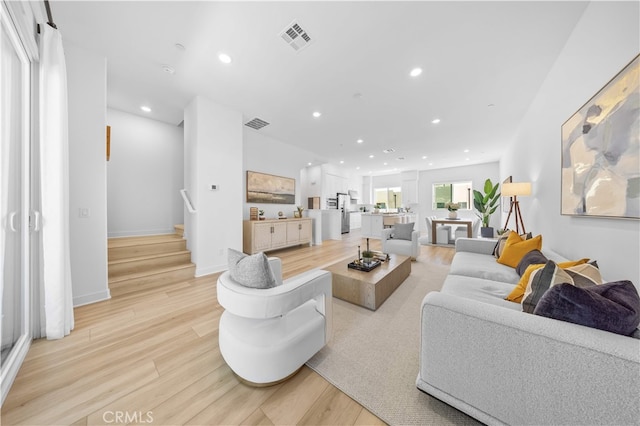 living area with light wood-type flooring, recessed lighting, stairway, and visible vents