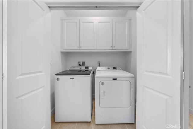 washroom with cabinet space, independent washer and dryer, and light tile patterned floors