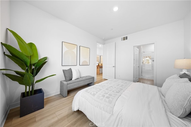 bedroom featuring baseboards, ensuite bath, light wood finished floors, and visible vents