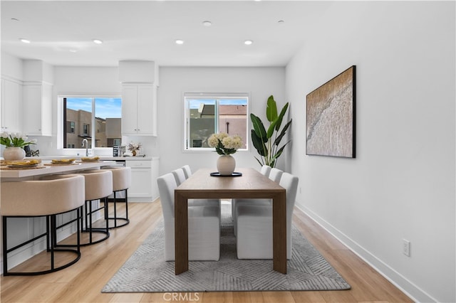 dining space with baseboards, light wood-style floors, and recessed lighting
