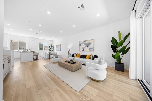 living room featuring visible vents, light wood-style flooring, and recessed lighting