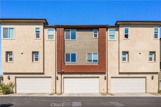 rear view of property featuring stucco siding and a garage