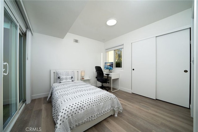 bedroom featuring a closet, visible vents, baseboards, and wood finished floors