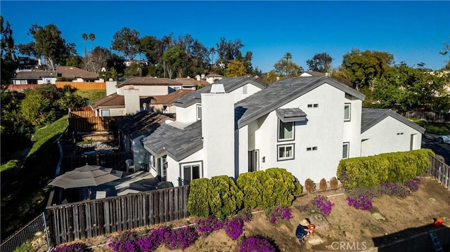 view of home's exterior with a residential view, fence, a chimney, and stucco siding