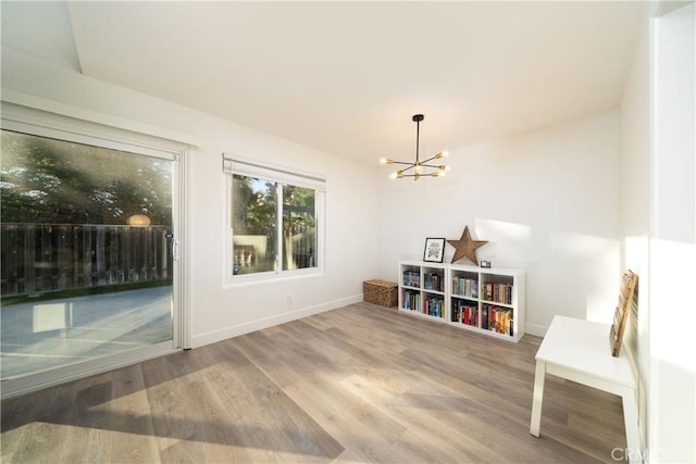 interior space with a notable chandelier, wood finished floors, and baseboards