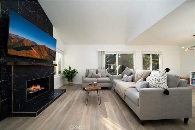 living room with lofted ceiling, a premium fireplace, baseboards, and wood finished floors