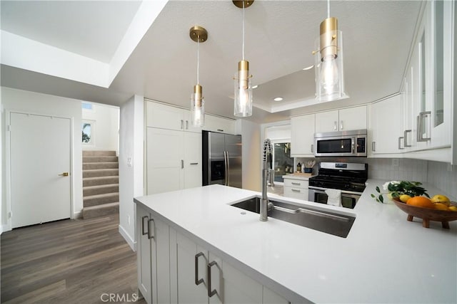 kitchen featuring a peninsula, white cabinets, appliances with stainless steel finishes, dark wood-style floors, and a tray ceiling