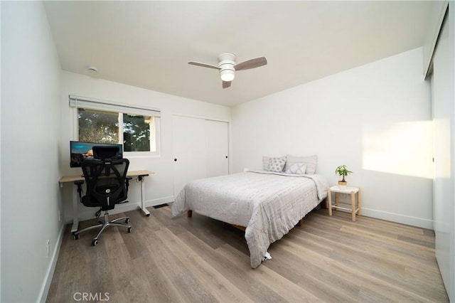 bedroom with a ceiling fan, a closet, baseboards, and light wood finished floors