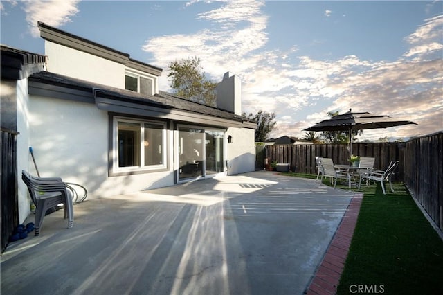 rear view of house featuring fence and stucco siding