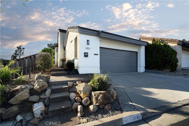 view of home's exterior featuring driveway, an attached garage, fence, and stucco siding