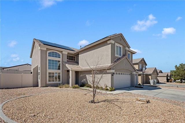 traditional home with driveway, a tile roof, fence, roof mounted solar panels, and stucco siding