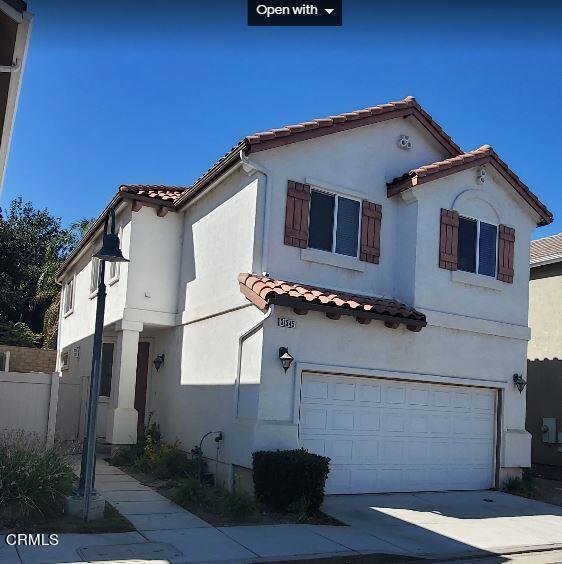 view of front facade with stucco siding, driveway, a tile roof, fence, and a garage