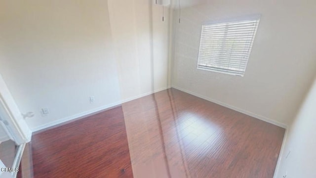 unfurnished room with baseboards and wood finished floors