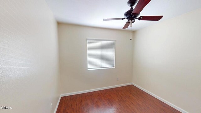 unfurnished room with a ceiling fan, baseboards, and wood finished floors