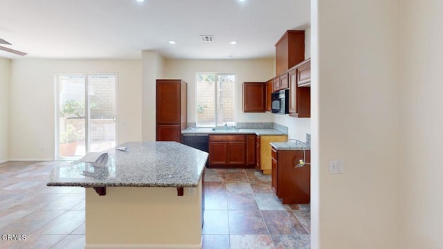 kitchen with a kitchen bar, a kitchen island, a sink, visible vents, and black appliances