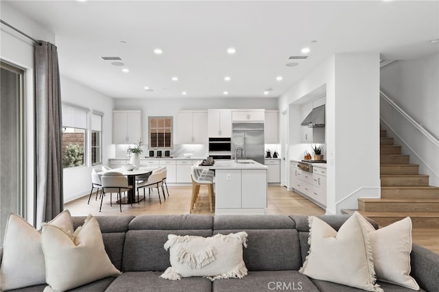 living room with recessed lighting, stairway, light wood-style floors, and visible vents