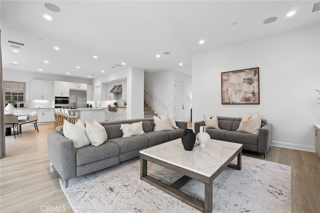 living room with light wood finished floors, visible vents, and recessed lighting