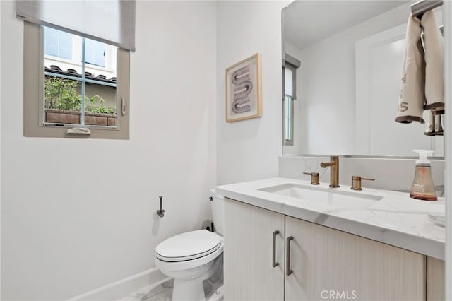 bathroom featuring vanity, toilet, baseboards, and marble finish floor