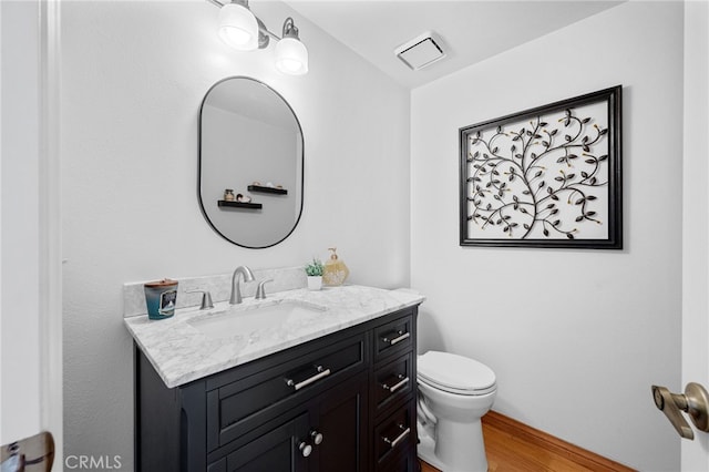 bathroom with visible vents, toilet, wood finished floors, and vanity