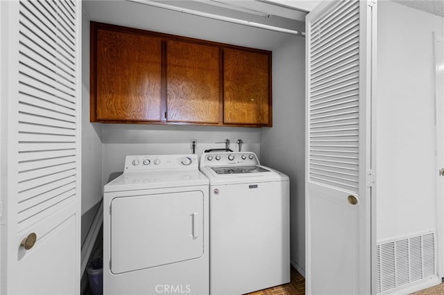 washroom featuring visible vents, cabinet space, and independent washer and dryer