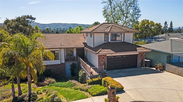 view of front facade with brick siding, a tile roof, an attached garage, and concrete driveway