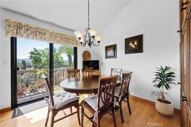 dining room featuring baseboards, lofted ceiling, light wood-style floors, a notable chandelier, and a textured ceiling