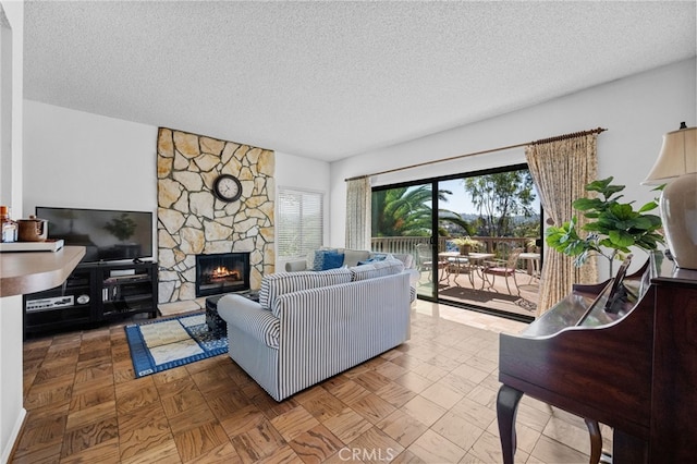 living room featuring a stone fireplace and a textured ceiling