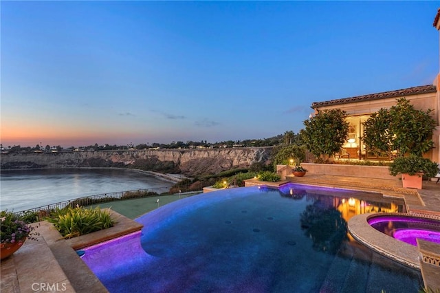 view of pool with a water view and a pool with connected hot tub