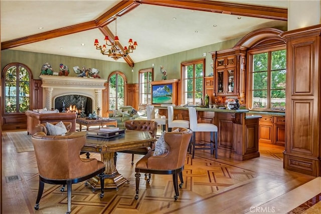 dining room featuring a chandelier, a wealth of natural light, a warm lit fireplace, and lofted ceiling with beams