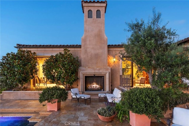 view of patio featuring a warm lit fireplace