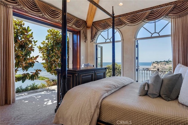 bedroom with carpet floors, access to outside, beam ceiling, and a water view