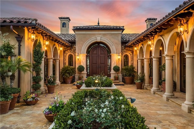 exterior space with a tile roof and stucco siding