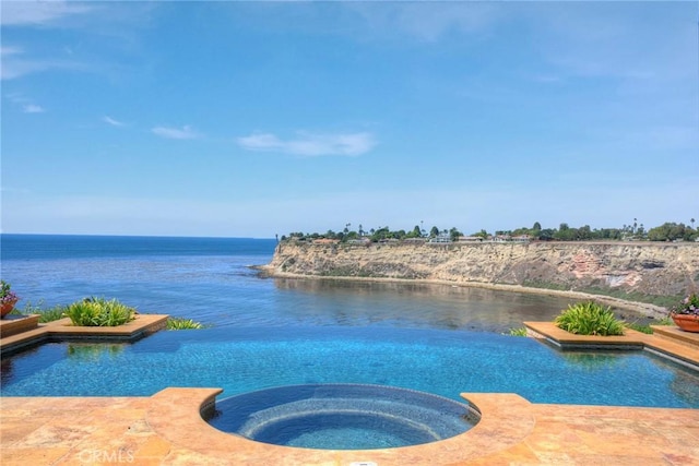 view of pool featuring a water view and a pool with connected hot tub